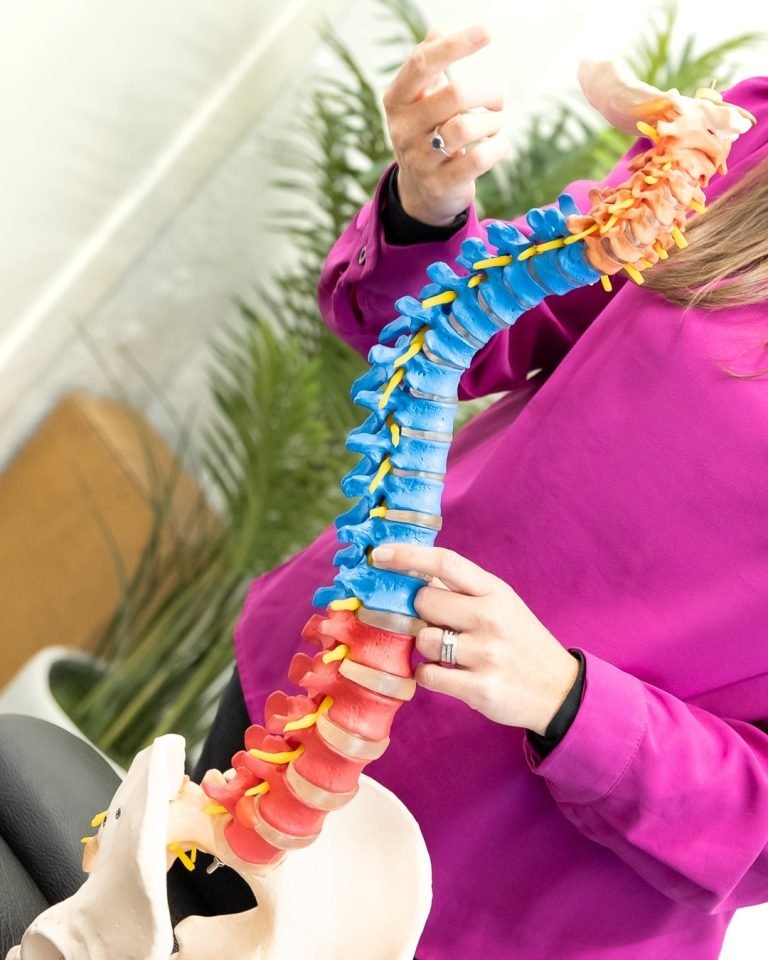 alt="Chiropractor Fiona using a spinal model to explain the root cause of back pain and how gentle adjustments restore natural alignment."