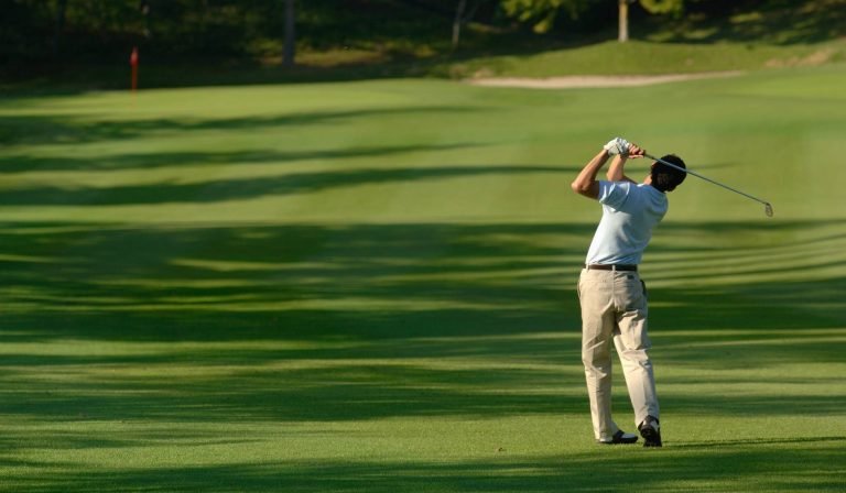 alt="A golfer at a golf course demonstrating the improved spinal rotation and mobility gained through chiropractic care."